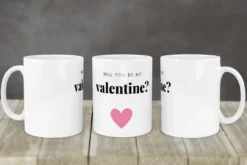 Kubek biały z napisem 'Will you be my valentine?' i różowym sercem, widok z trzech stron.